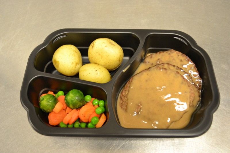En matlåda med kokt potatis, köttbiffar, brunsås och grönsaker