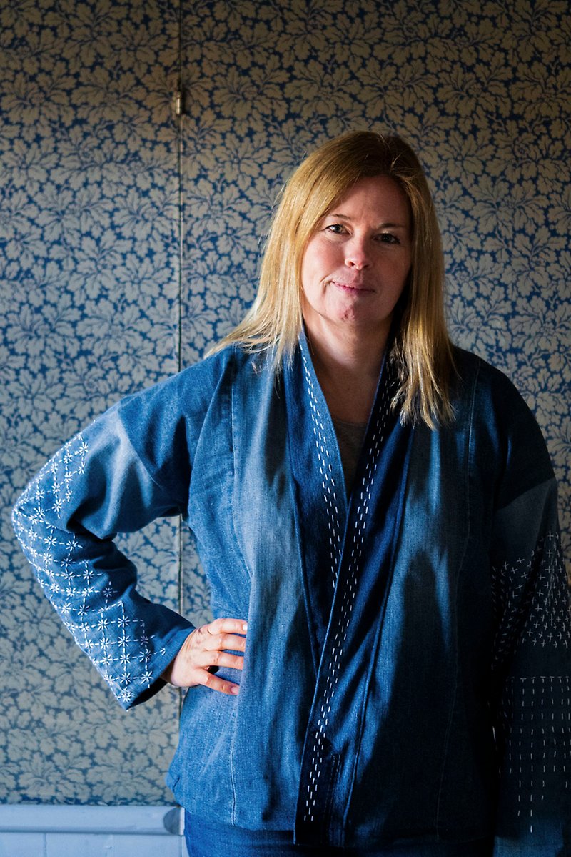 Malin Svedberg poserar i en mörkblå jacka med mönster broderat på ärmarna. 